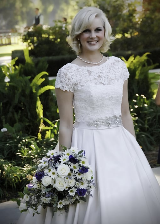 Bride with bouquet and groom in distant background